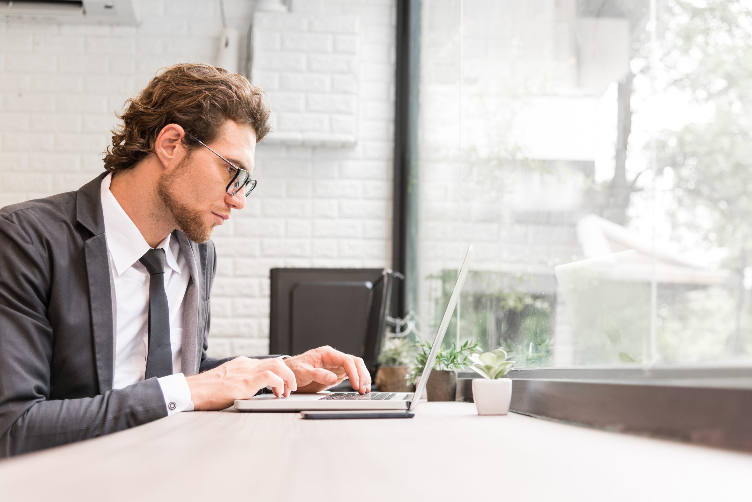 young employee in a business suit working on a laptop