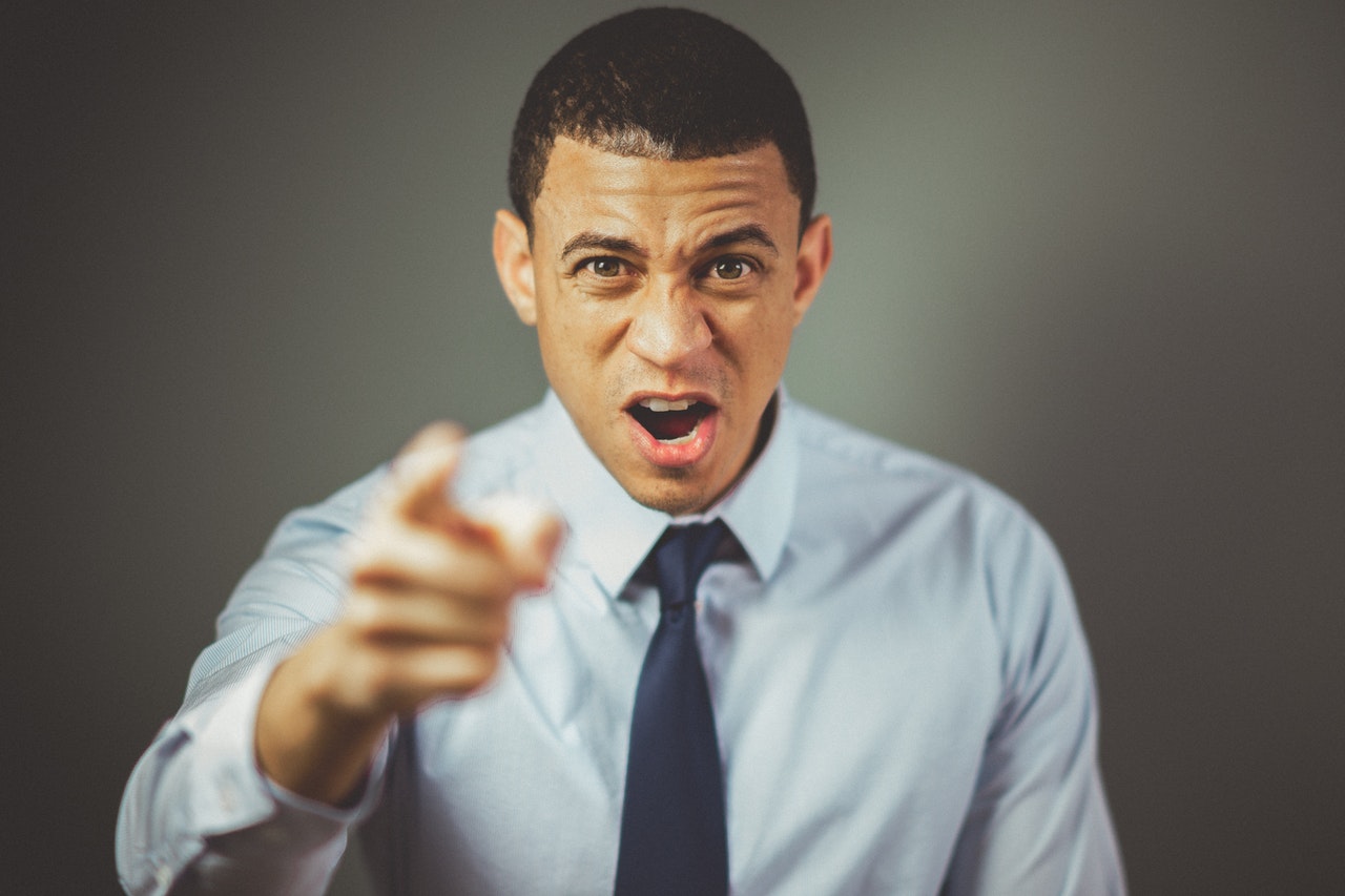 Angry man pointing at the camera. He's wearing a dress shirt and tie