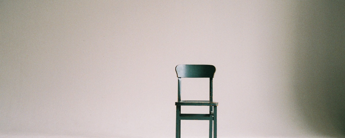 An empty wooden chair sitting in an empty room