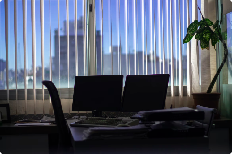 2 computers on a desk in front of a window